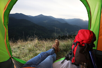 Fototapeta premium Woman resting inside of camping tent in mountains at sunset, closeup