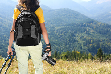 Photographer with backpack, camera and tripod surrounded by breathtakingly beautiful nature