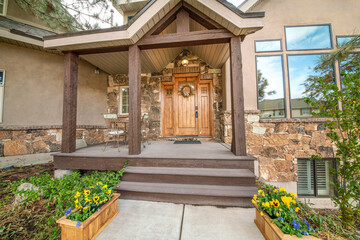 Entrance of a house with flowers on the wooden boxes at the front of the porch