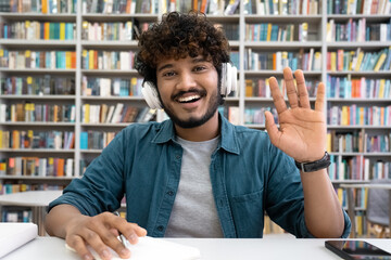 Indian student in headset greeting classmates or teacher looking at camera