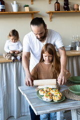 Obraz na płótnie Canvas A family with three children has fun baking together.Dad And Daughter Laughing And Cooking Healthy Food Front View Lifestyle Concept . Candid