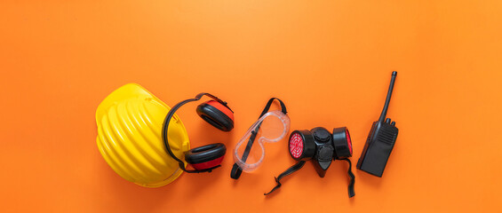 Work wear safety protection equipment, orange color background, personal protective gear, top view