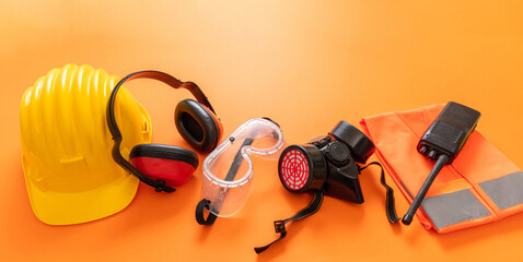 Work wear safety protection equipment, orange color background, personal protective gear, top view