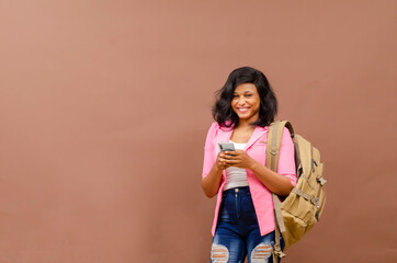 Happy and excited cute young college student with phone and backpack isolated over a white studio...
