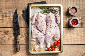 Cooking Raw spatchcocked whole chicken with garlic and thyme in baking dish. Wooden background. Top view