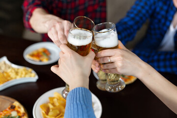 Clinking beer near pizza in bar