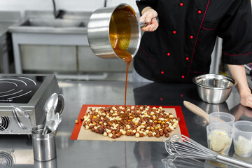 Pastry chef pours hot syrup, caramel on hazelnuts to make praline