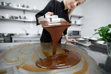 Close-up of a pastry chef using spatulas tempering molten chocolate