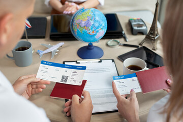 Close-up of passports and tickets in the hands of travelers at a travel agency - obrazy, fototapety, plakaty