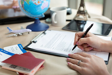 A female travel agent in the office signs a contract, close-up - obrazy, fototapety, plakaty