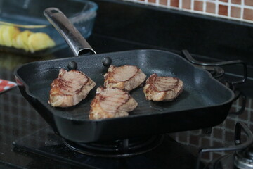 Peça de carne picanha inteira e com cortes crua e grelhada em frigideira