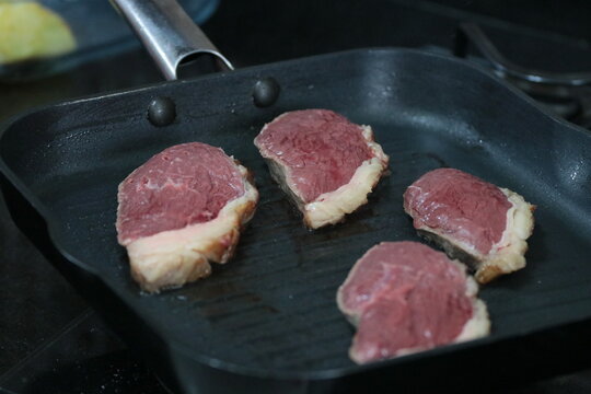 Peça de carne picanha inteira e com cortes crua e grelhada em frigideira