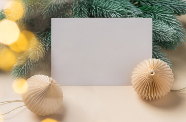 Paper blank, christmas decorations, fir branches and blurred lights. Christmas greeting card mockup