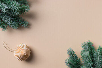 Christmas frame with paper decoration and fir tree branches on beige background. Winter holiday and celebration concept. top view