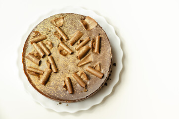 Digestive biscuit base with chocolate cheesecake and pockets of salted caramel sauce, topped with chocolate ganache, milk chocolate curls, and gold shimmer