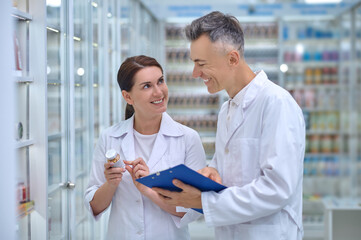 Fototapeta premium Woman with medicine and man with folder in pharmacy
