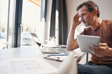 Fototapeta premium Serious aged man making calculations in office