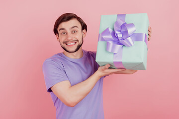 Photo of handsome cheerful excited young man happy positive smile holding gift box isolated over...
