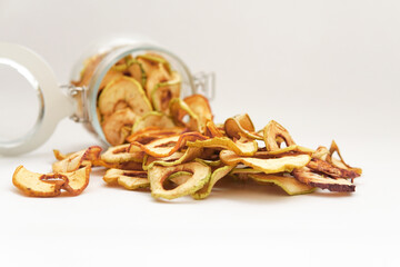 dried apples poured out of a jar on a white background