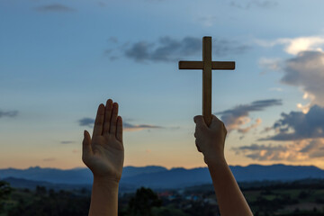 Christian, Christianity, Religion copy space background. Human praying and holding christian cross for worshipping God at sunset background.silhouette