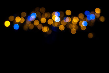Beautiful background of defocused shiny blue and yellow round circles isolated on black background.