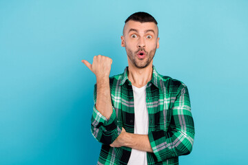 Photo of amazed shocked young man point finger empty space sale news thumb isolated on blue color background