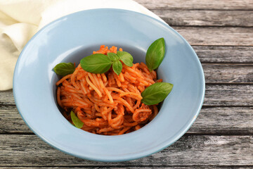 Delicious Italian spaghetti with tomato sauce and fresh basil, healthy cooked pasta for dinner and lunch in a gourmet restaurant.