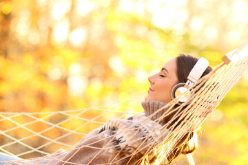 Happy woman enjoying listening to music in autumn