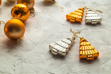 Gold and silver Christmas tree toys on a light blurry background.