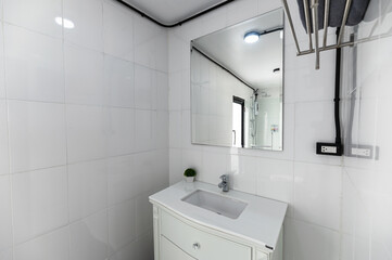 White bathroom with washbasin, faucet and mirror