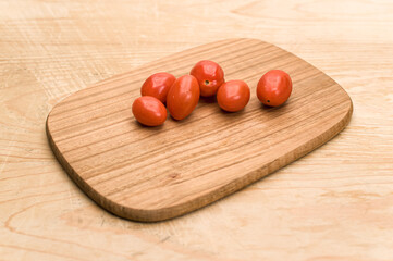 fresh datterini tomatoes on a wooden chopping board on a rustic wooden background
