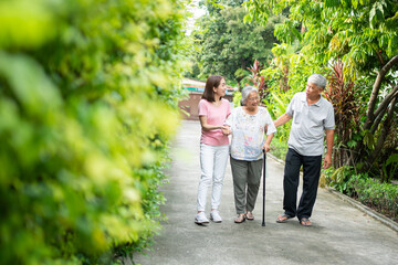 Obraz premium Happy family walking together in the garden. Old elderly using a walking stick to help walk balance. Concept of Love and care of the family And health insurance for family