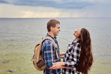 Lovers in a lake. Young couple in love sitting on the park ground near the water while these young man playing guitar in sunset time.
