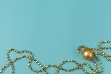 Golden Christmas and new year decorations. Beads and ball on light blue background. Top view