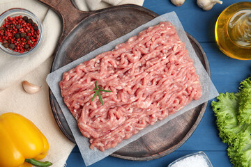 Raw chicken minced meat and ingredients on blue wooden table, flat lay