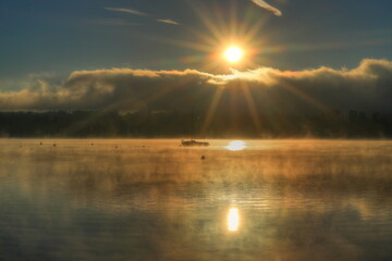 Fischerboot im Simssee bei Sonnenaufgang und Morgennebel