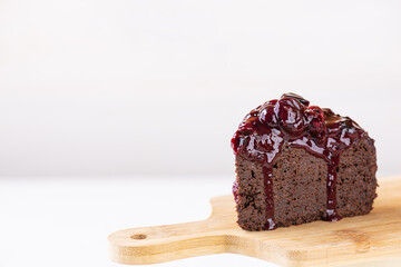 A piece of chocolate cake with berry jam on a wooden board. Sugar, gluten and lactose free, vegan. Horizontal orientation, copy space.