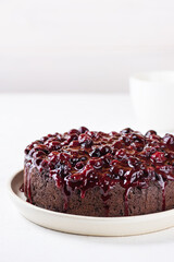 Chocolate cake with berry jam on a white plate. Sugar, gluten and lactose free, vegan.
