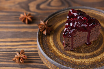 A piece of brownie with berry jam and anise on a plate. Sugar, gluten and lactose free, vegan.