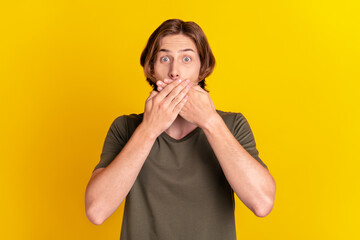 Photo of young guy close mouth hands oops mistake tell secret trouble isolated over yellow color background