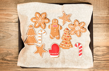 Christmas cookies painted with icing on a baking sheet on a wooden table
