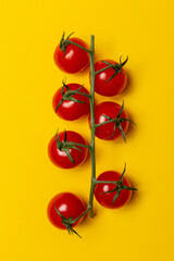 a fresh branch with seven cherry tomatoes on a yellow background