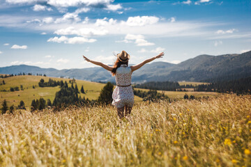 Hiker woman standing with hands up achieving the top. Girl welcomes a sun. Conceptual design. Successful woman hiker open arms on sunrise mountain top. Girl in dress in the mountains.