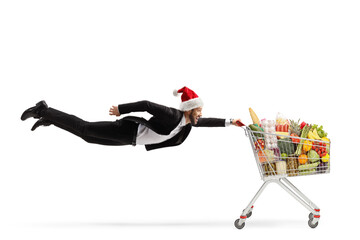Full length shot of a businessman with a christmas santa claus hat flying and holding a shopping...