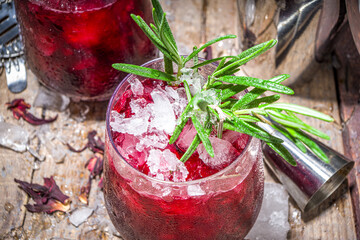 Cold autumn winter hibiscus cocktail with rosemary and crushed ice, copy space