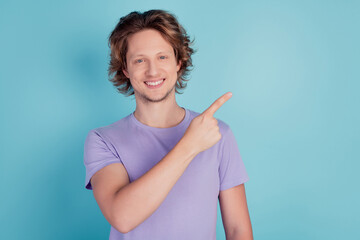 Photo of cheerful young guy point finger empty space advert promotion suggest sale isolated on teal color background
