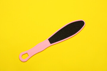 Pink foot file on yellow background, top view. Pedicure tool
