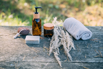Natural bathroom accessories. Sustainable lifestyle. Plastic free concept. Wooden brushe, cream, reusable glass container with shampoo, foot stone, body oil, natural soap and other items.