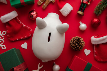 Festive Christmas financial savings concept. White piggy bank money box with presents and decorations