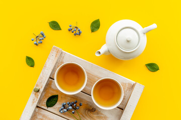 Ceramic white teapot and black tea in two cups, top view